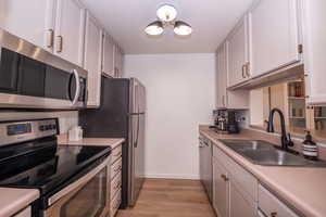 Kitchen featuring stainless steel appliances, light countertops, and light wood-style floors