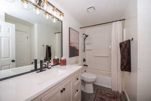 Bathroom featuring vanity, shower / tub combo with curtain, and dark tile patterned flooring