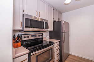 Kitchen with stainless steel appliances, light countertops, and light wood-style flooring