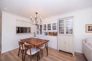 Dining area featuring crown molding, light wood-type flooring, and hanging lights