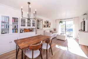 Dining area featuring light wood-type flooring, a wall mounted mini split, and crown molding