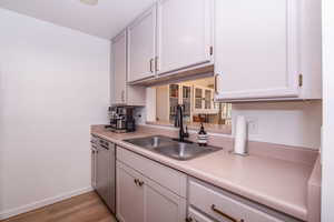 Kitchen featuring stainless steel dishwasher, light wood finished floors, and light countertops