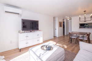 Living area with light wood-style floors, ornamental molding, and a chandelier