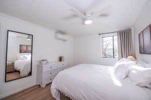 Bedroom featuring dark wood-style flooring, ornamental molding, and a ceiling fan