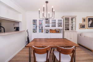Dining area featuring light wood-style floors, crown molding, and suspended lighting