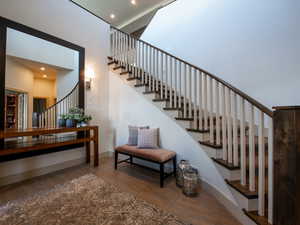 Stairs with wood finished floors, recessed lighting, and a high ceiling