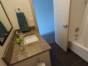 Bathroom featuring shower / bathtub combination with curtain, vanity, and dark tile patterned floors