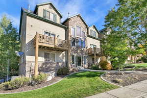 Back of house with stone siding and a yard