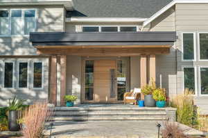 View of exterior entry with a patio and roof with shingles