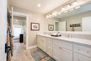 Bathroom with double vanity, light wood finished floors, and recessed lighting