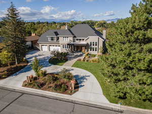 View of front facade featuring concrete driveway, covered porch, a chimney, a garage, and a front lawn