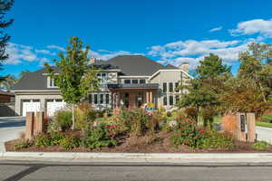 View of front of property featuring covered porch, a chimney, a garage, and driveway