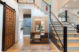Staircase with a barn door, a high ceiling, wood-type flooring, and recessed lighting