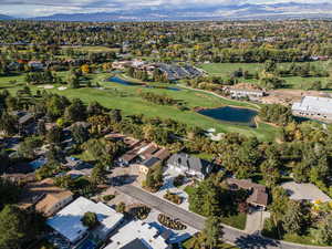 View of property location featuring a water and mountain view, a golf course, and nearby suburban area