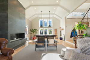Living room with light wood-style flooring, vaulted ceiling, and a tile fireplace