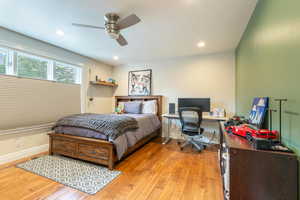 Bedroom 1 featuring light wood finished floors, a desk, ceiling fan, and recessed lighting