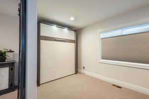Carpeted spare room with murphy bed