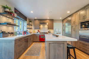 Kitchen featuring a breakfast bar, open shelves, stainless steel appliances, recessed lighting, and backsplash