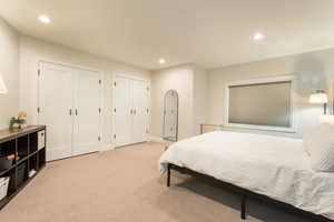Bedroom featuring multiple closets, light carpet, and recessed lighting