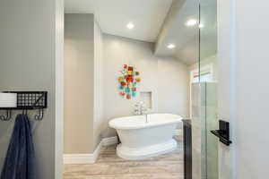 Full bath featuring a freestanding bath, light wood finished floors, and recessed lighting