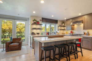 Kitchen with a kitchen breakfast bar, light wood-style flooring, a kitchen island, open shelves, and recessed lighting