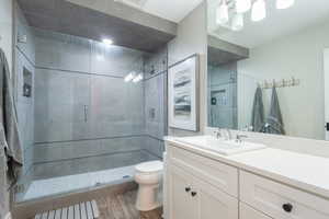 Full bath with vanity, a shower stall, and dark wood-type flooring