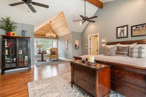 Primary bedroom with light wood-type flooring, hanging lights, vaulted ceiling, and ceiling fan