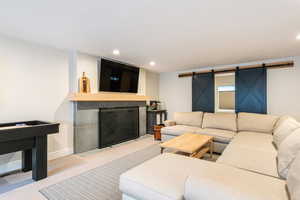 Carpeted living room with a barn door, a tile fireplace, and recessed lighting