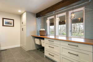 Detailed view of wood counters, decorative light fixtures, white cabinetry, and backsplash