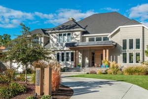 View of front of property with a chimney, a shingled roof, a front lawn, and a patio area