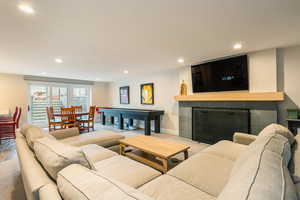 Carpeted living area featuring a tiled fireplace and recessed lighting