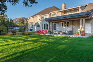 Rear view of property featuring a patio area, an outdoor hangout area, a chimney, a yard, and a balcony