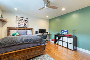 Bedroom 1 featuring light wood-style floors, ceiling fan, recessed lighting, and a desk