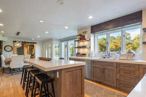 Kitchen featuring a barn door, wood finish cabinetry, stainless steel dishwasher, a kitchen island, and light wood finished floors