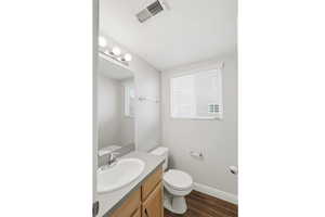 Half bathroom featuring vanity and dark wood-style flooring