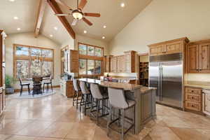 Kitchen featuring a breakfast bar, stainless steel built in refrigerator, recessed lighting, lofted ceiling, and a kitchen island