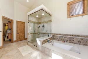 Full bathroom with a shower stall, a garden tub, light tile patterned floors, and vaulted ceiling