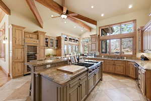 Kitchen with beverage cooler, a breakfast bar area, ceiling fan, vaulted ceiling, and a center island