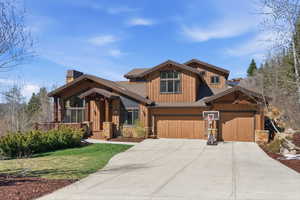 View of front of property featuring driveway, a chimney, a front yard, board and batten siding, and an attached garage