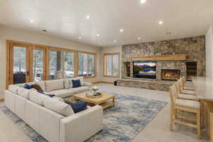 Living area with a stone fireplace, recessed lighting, and light carpet