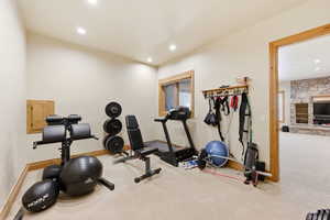 Exercise room featuring carpet, a stone fireplace, and recessed lighting