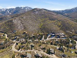 Aerial view of property and surrounding area with a mountain backdrop and nearby suburban area