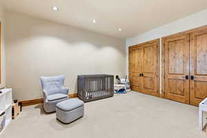 Carpeted bedroom with a nursery area, recessed lighting, and two closets