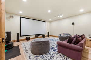 Home theater featuring light wood-style flooring and rail lighting