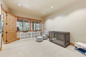 Bedroom featuring a crib, light carpet, and recessed lighting