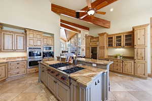 Kitchen with stainless steel appliances, light stone countertops, a kitchen bar, wine cooler, and lofted ceiling