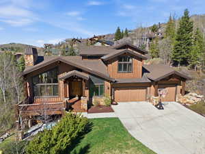 View of front of home with concrete driveway, a chimney, a shingled roof, and a garage