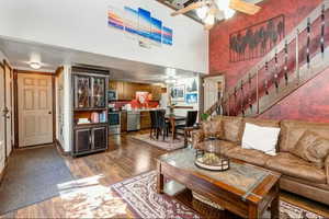 Living room with dark wood-style floors, a ceiling fan, and a high ceiling