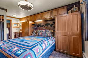 Bedroom with ornamental molding, ensuite bathroom, dark wood-style flooring, and a ceiling fan