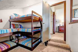 Bedroom with light colored carpet and a textured ceiling